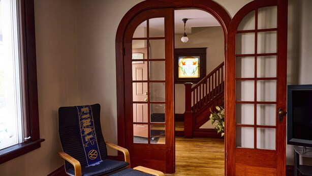 Un pasillo con una silla y una puerta de madera, además de una escalera.