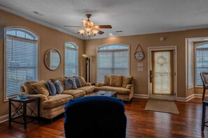 A living room with a sectional sofa, a coffee table, a floor lamp, and a ceiling fan.