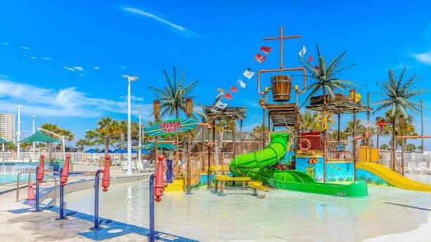 A water park with a green slide, a yellow slide, and a pool area. - Ocean Lakes T36 (Myrtle Beach)