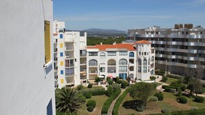 A multi-story residential building with balconies, a courtyard with greenery, and a view of distant hills. - Superb apartment completely renovated 4EST211 (LE BARCARES)