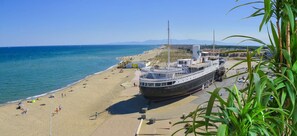 A large cruise ship docked at a beach with a sandy shore, clear blue water, and distant mountains. - Superb apartment completely renovated 4EST211 (LE BARCARES)