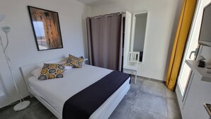 A bedroom with a bed, a painting, a chair, and a bathroom door. - Superb apartment completely renovated 4EST211 (LE BARCARES)