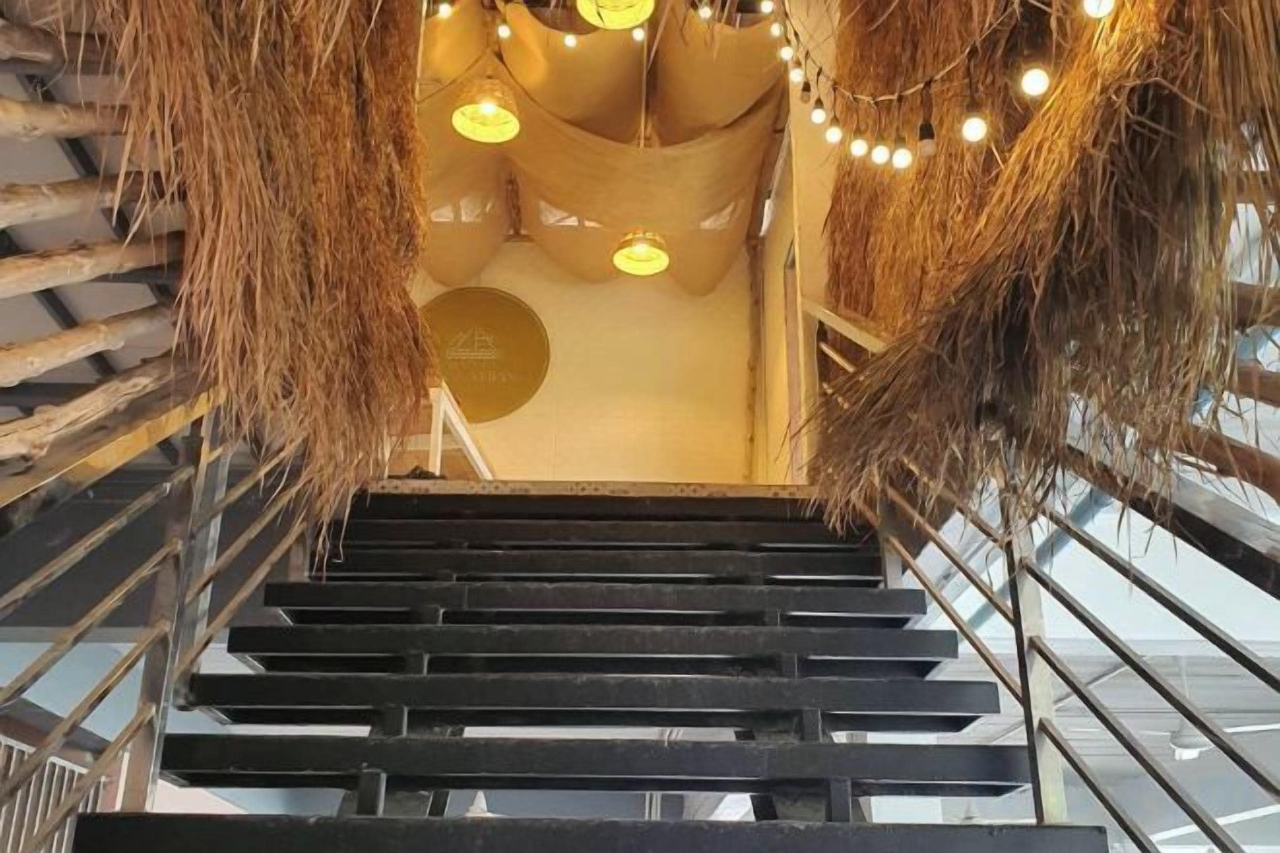 A staircase with a modern design, featuring a metal railing and a ceiling with hanging lights.