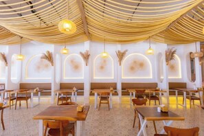 Un restaurant avec des tables et des chaises en bois, un sol à motifs et un plafond au design original.