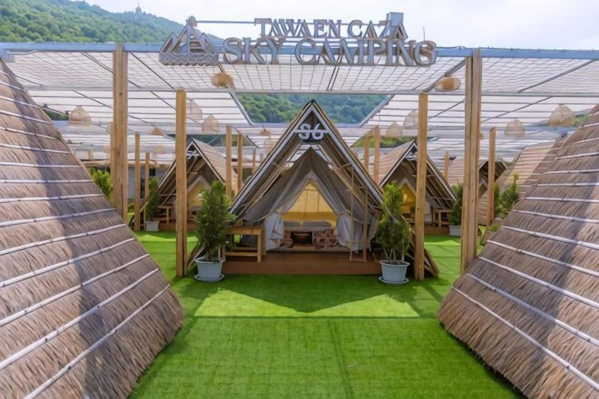 A hotel with thatched-roof cabins, a central building with a sign, and a green lawn.