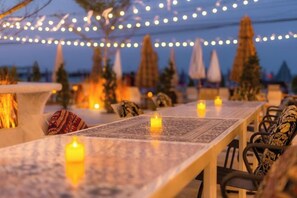An outdoor dining area with tables, chairs, and string lights.