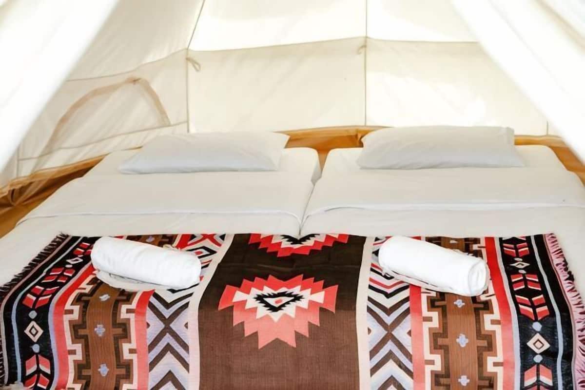 A tent with two beds, each with pillows and blankets.