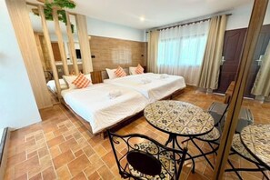 Habitación de hotel con dos camas, una mesa redonda y una silla.