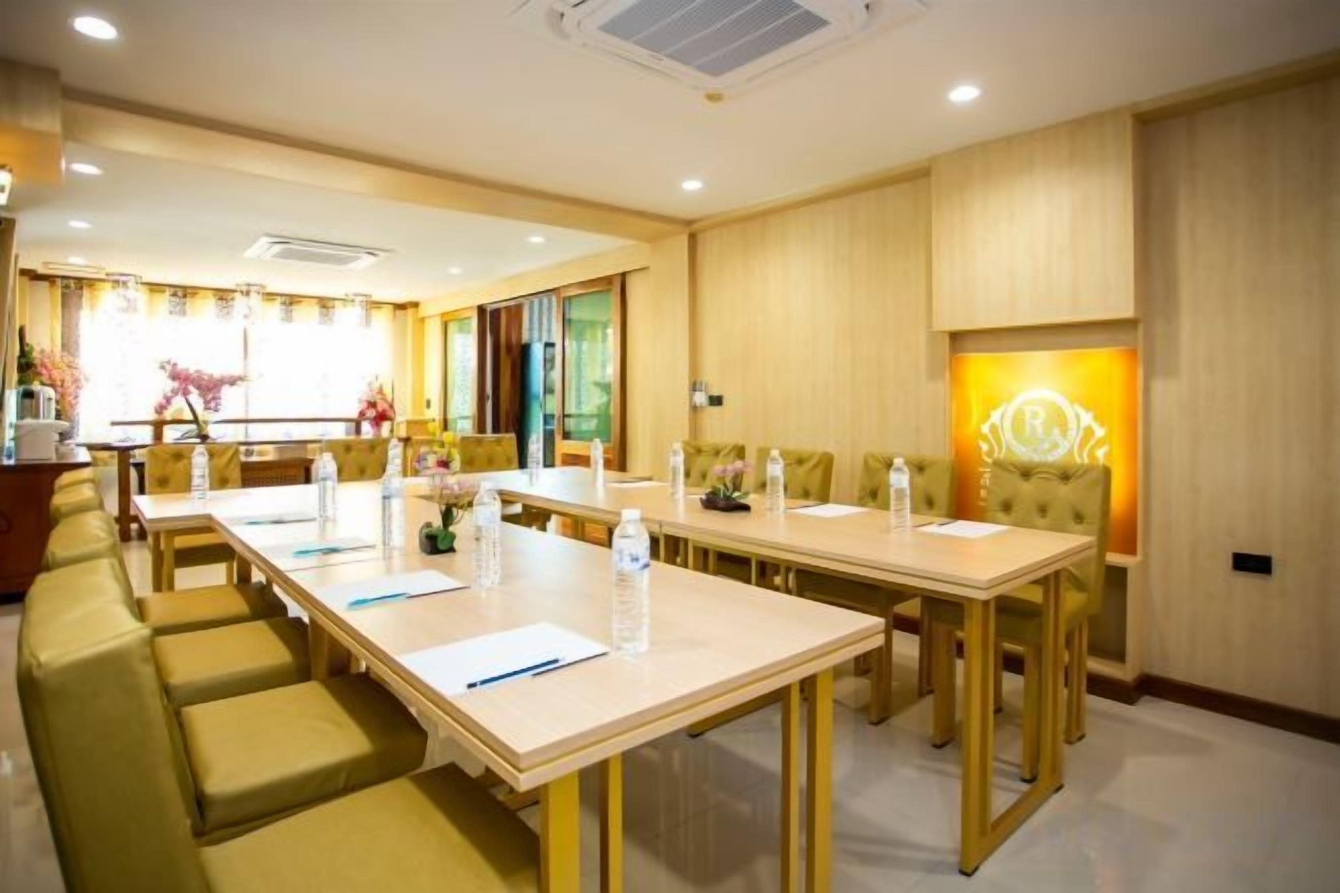 A hotel conference room with long tables, chairs, and a sofa.