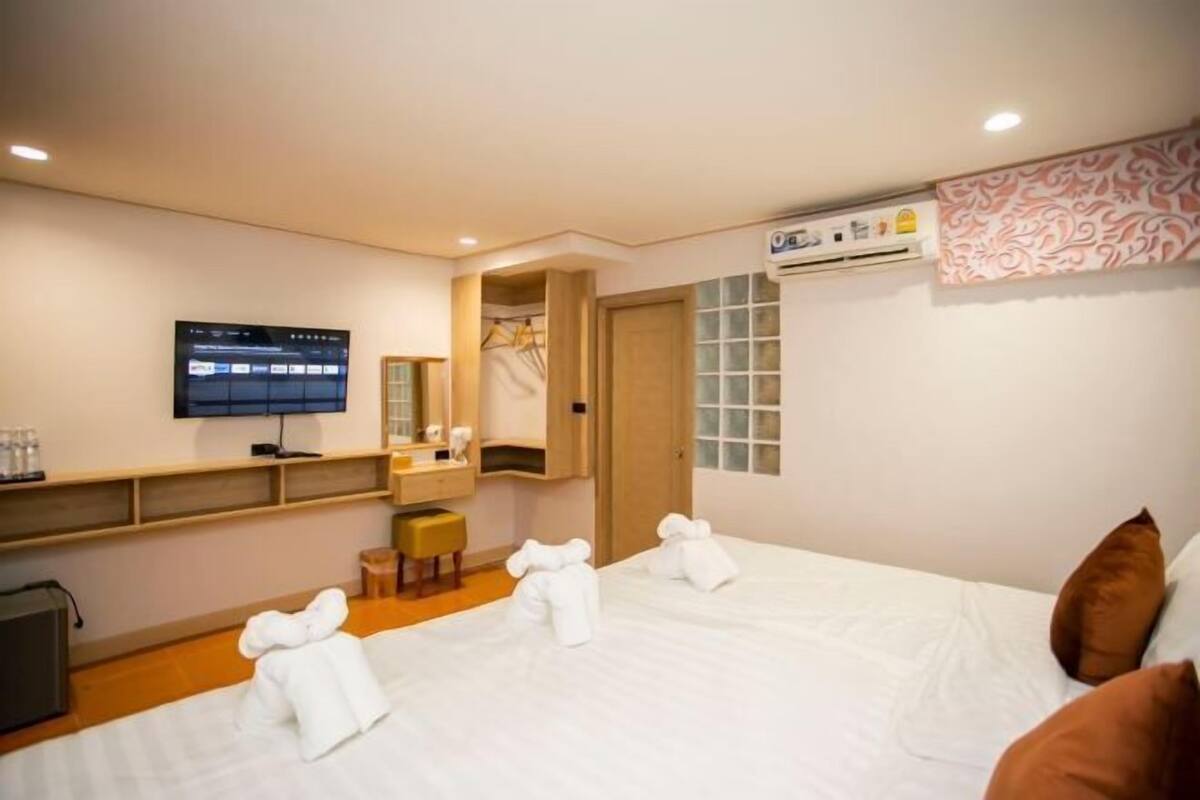 Hotellihuone, jossa on sänky, televisio, työpöytä ja vaatekaappi.