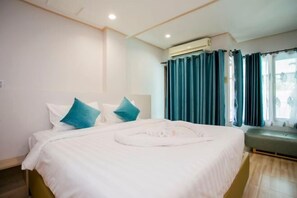 Una habitación de hotel con cama, un banco y una ventana con cortinas.