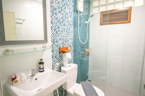 Un baño con lavamanos blanco, un espejo, inodoro y zona de ducha.