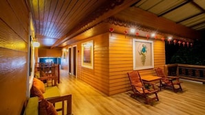 A wooden deck with a dining area, including tables and chairs, and a wall with framed artwork.