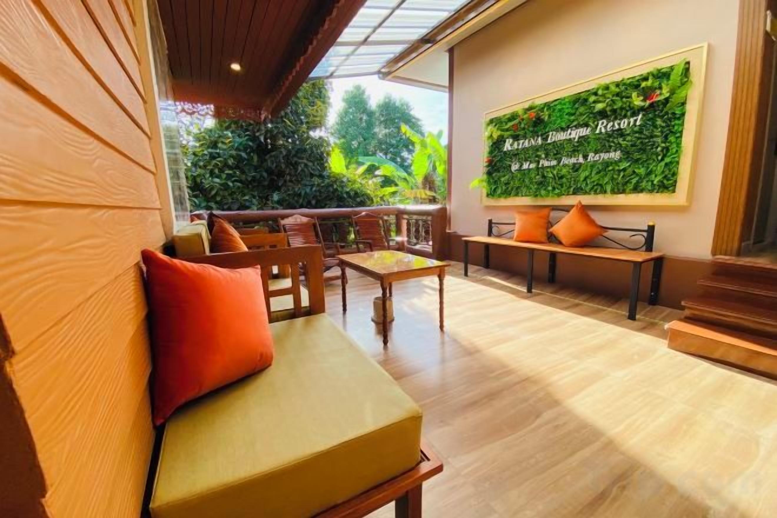 A wooden bench with cushions, a wooden table, and a sofa with a red cushion. There is a green wall with text and a wooden floor.