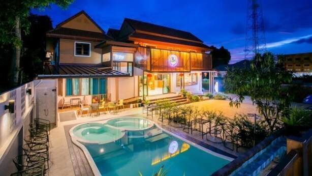 A hotel with a swimming pool, outdoor seating, and a well-lit entrance.