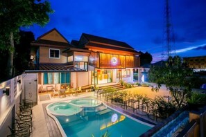 Un hotel con piscina, zona de estar al aire libre y una entrada bien iluminada.