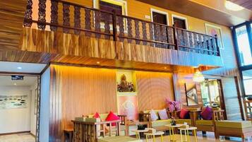 Un hall d’hôtel doté d’un balcon, d’un espace salon et d’un comptoir d’accueil.