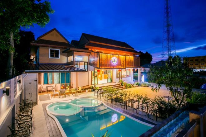 Un hotel de dos pisos con piscina y zona de estar al aire libre.