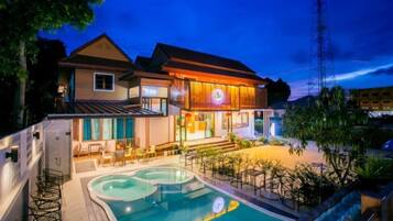 Un hotel de dos pisos con piscina y zona de estar al aire libre.