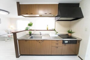 A compact kitchen with wooden cabinets, a stainless steel sink, and a dishwasher. - Awaji Seaside Resort in Ikuha (Awaji City)