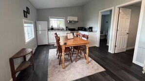 A compact kitchen with white cabinets, a dining table with chairs, and a small window.