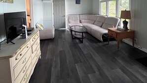 A spacious living room with a large sectional sofa, a coffee table, and a TV on a dresser.