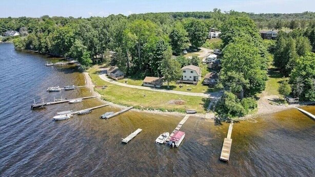 A lakeside property with docked boats, a house, and a boat ramp.