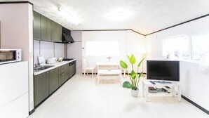 Una cocina moderna con armarios oscuros, un microondas y un comedor con una mesa y sillas blancas.