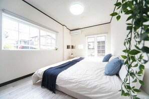 Une chambre avec un grand lit, une fenêtre et une plante.