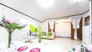 Una habitación moderna y luminosa con una mesa de comedor para dos personas, un sofá y una cama con dosel.