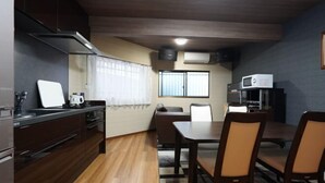 Uma cozinha compacta com área de refeições, armários de madeira, micro-ondas e uma janela com cortinas.