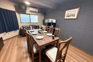 A dining area with a long wooden table, chairs, and a sofa. - Japanese cottage Han (Osaka)