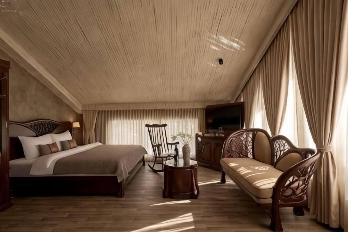 A bedroom with a bed, a chair, a sofa, a small table, and a television.