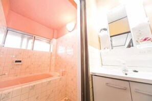 Casa de banho com banheira, chuveiro e lavatório com espelho.