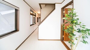 Ein moderner Flur mit Treppe, großem Fenster und Topfpflanze.
