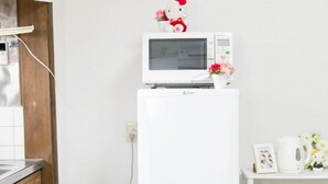 Eine Küche mit einer Mikrowelle und einem Kühlschrank, einem Holzkästen und einem Regal mit einer Hello Kitty Dekoration.