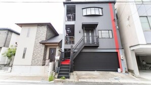 Ein mehrgeschossiges Wohngebäude mit Garage, Treppe und Balkon.