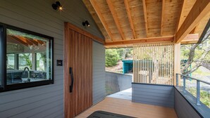 A covered outdoor area with a wooden deck, a sliding door, and a window overlooking a backyard. - Nutic Izu (Ito)