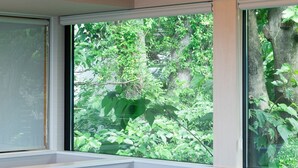 A room with a built-in bench, large windows, and exposed wooden beams. - Nutic Izu (Ito)