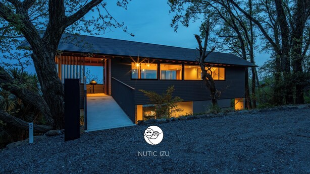 A modern house with a covered porch, large windows, and a gravel driveway. - Nutic Izu (Ito)
