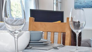 Ett matbord med en trästol, en tv och en målning som föreställer ett kustlandskap.
