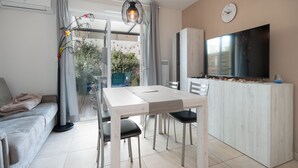 A modern living space with a dining area, a sofa, a TV, and a kitchen area.