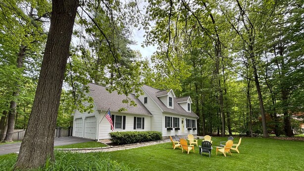 A house with a well-maintained lawn and outdoor seating area with Adirondack chairs.