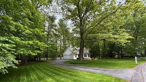 A residential property with a well-maintained lawn, a driveway leading to a garage, and a house with a porch.