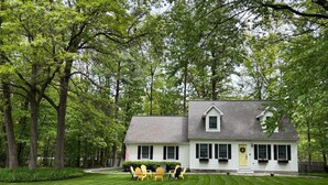 A two-story house with a well-maintained lawn and a small patio area with outdoor furniture.