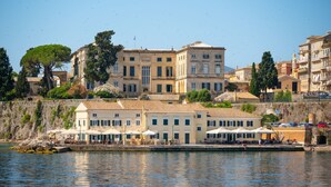 Un edificio frente al mar con varios balcones, una terraza con asientos al aire libre y vistas al océano.