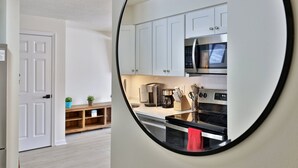 A modern kitchen with white cabinets, a stainless steel microwave, a coffee maker, and a stove.