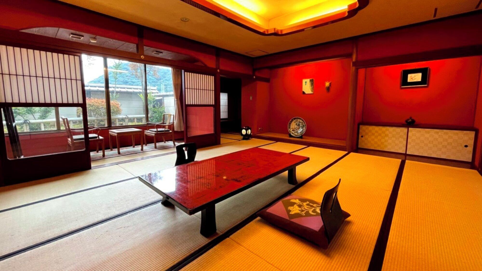 Une pièce avec un sol recouvert de tatamis, une petite table, des chaises et des portes coulissantes.
