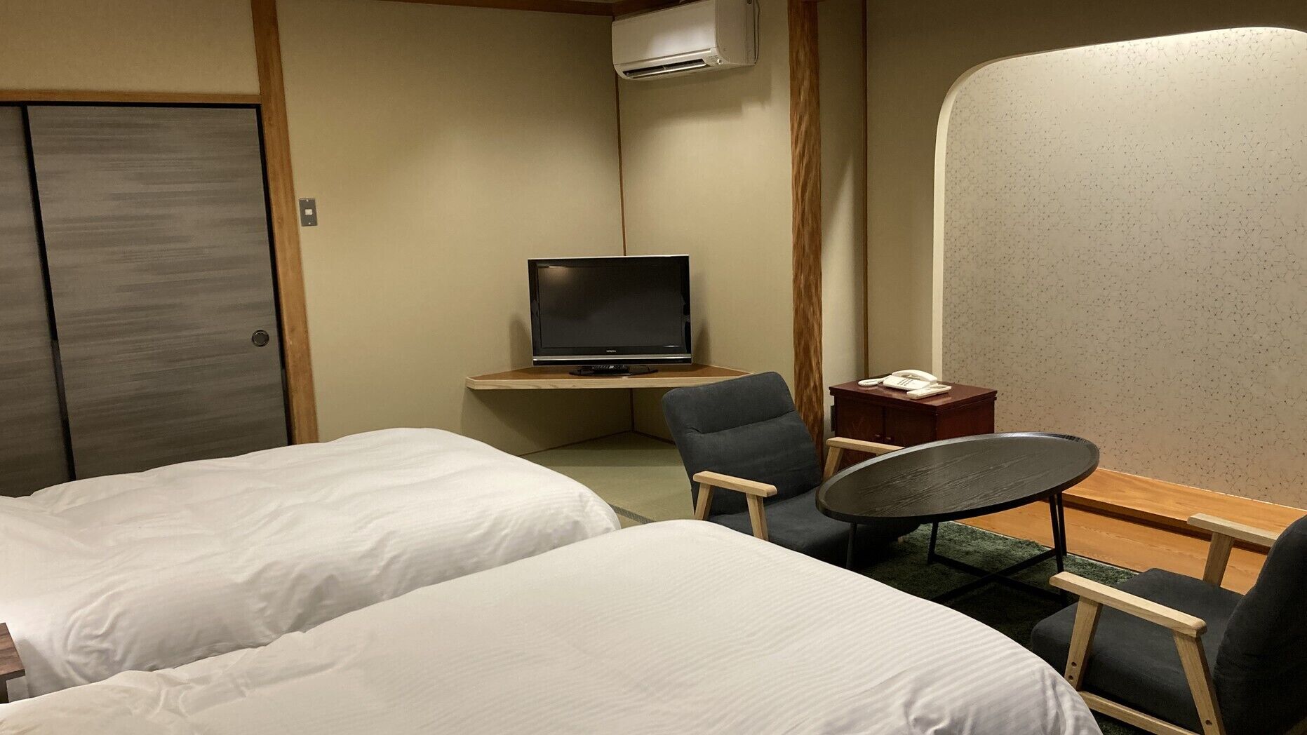 Une chambre d’hôtel avec deux lits, une télévision, un bureau avec une chaise et un téléphone.