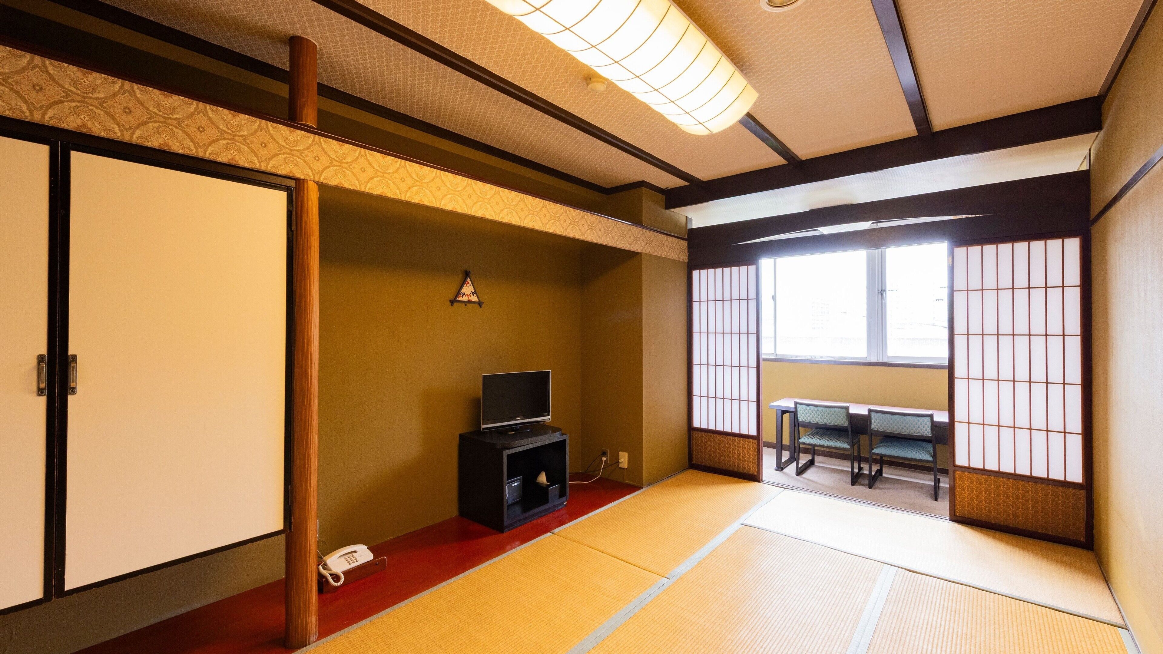 Une pièce de style japonais traditionnel, avec un sol recouvert de tatamis, une télévision, un téléphone et un paravent en papier.